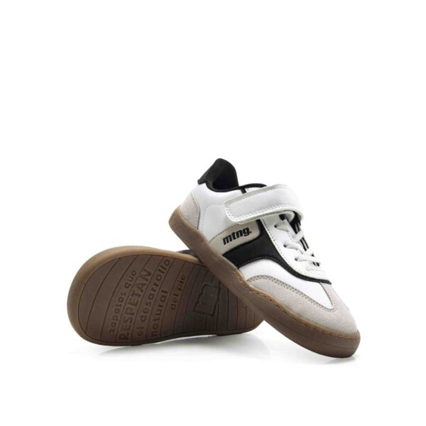 zapatilla respetuosa infantil Mustang Modern blanca y negra vista lateral y suela