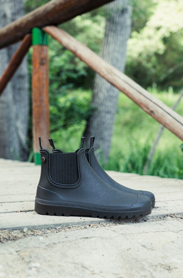 Par de botas de agua Igor Alex en negro, foto de estilo de vida sobre tarima de madera