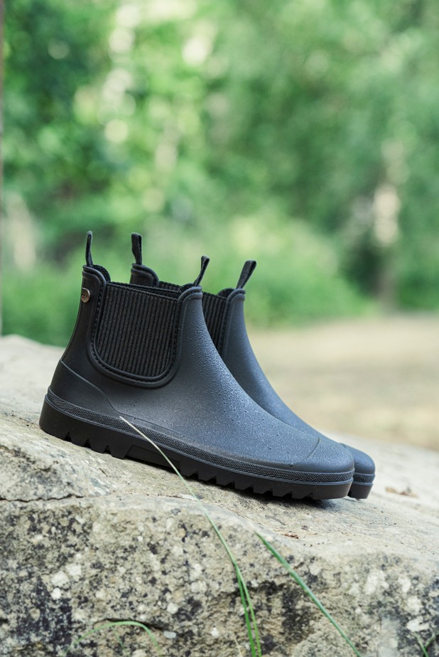Par de botas de agua Igor Alex en negro, foto de estilo de vida en el bosque sobre la piedra
